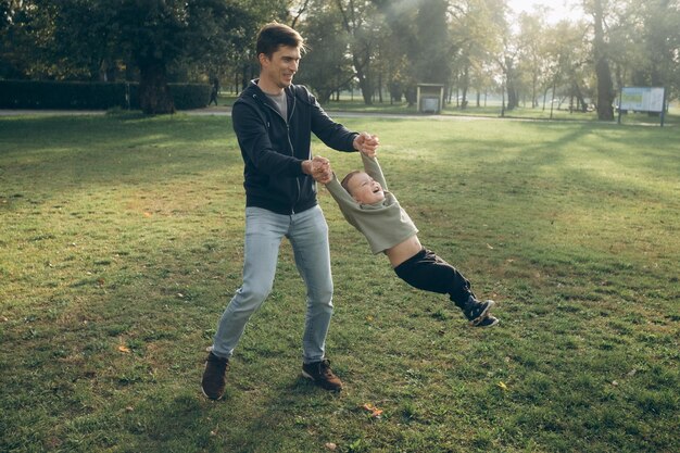 man circles a child on a green meadow the child laughs