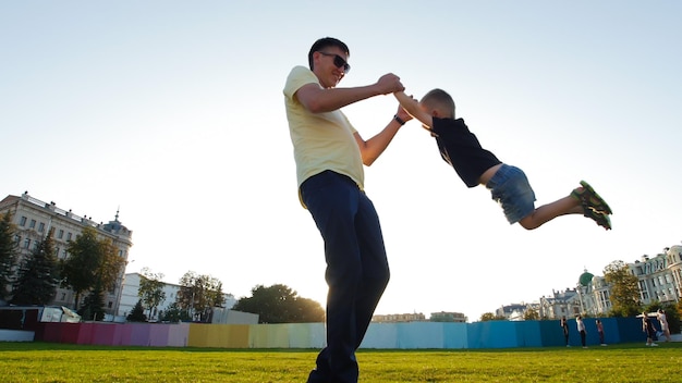 Man cirkelt een kleine jongen hand in hand in het park de zon schijnt