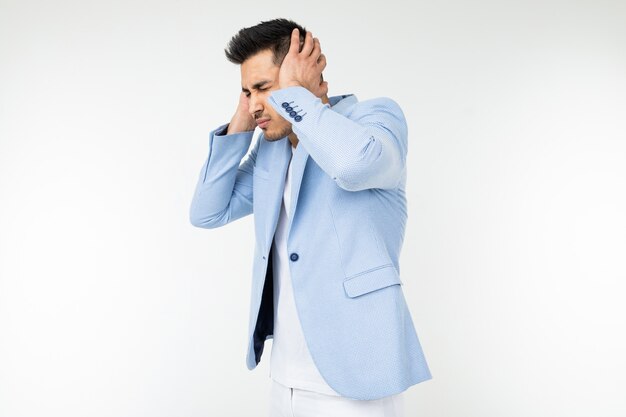 Man in a classic blue jacket covers his ears from loud noise on a white background