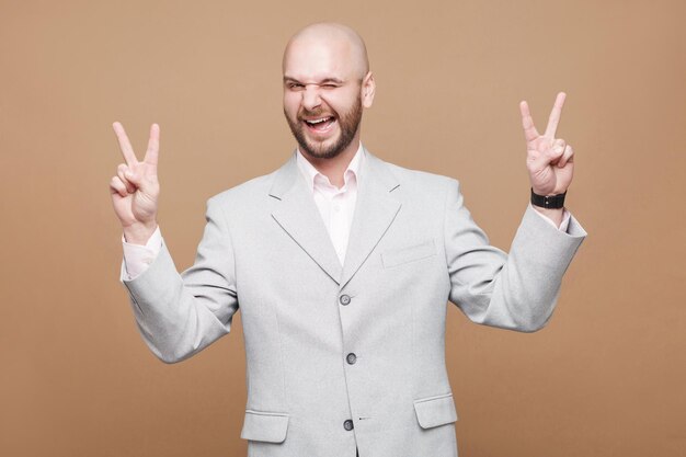 Man in classic light gray suit standing looking at camera winking with peace or victory sign