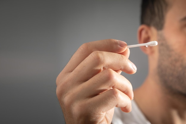 Man clean his ear using cotton bud