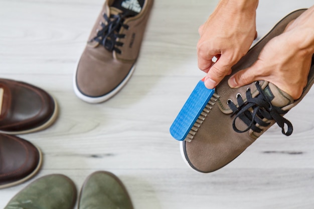 Фото Человек чистит и полирует кожаную обувь щеткой на деревянном фоне