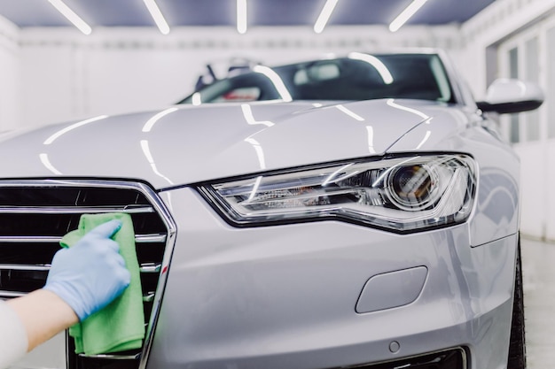 A man cleaning car with microfiber cloth, car detailing (or valeting) concept. Selective focus.