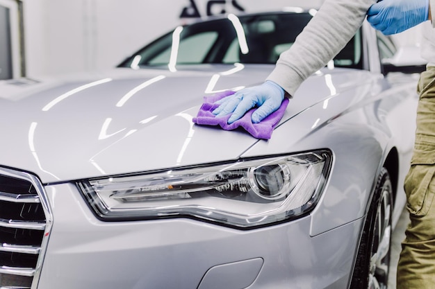 A man cleaning car with microfiber cloth, car detailing (or valeting) concept. Selective focus.