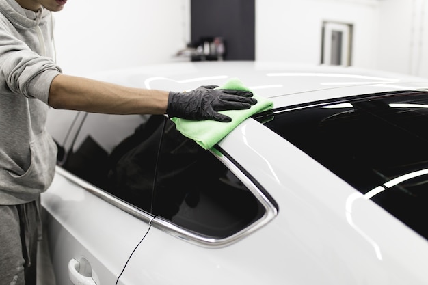 A man cleaning car with microfiber cloth, car detailing (or valeting) concept. Selective focus.