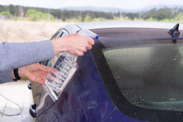 Uomo che pulisce auto con flacone spray. autolavaggio.