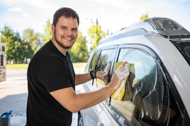 Man cleaning car with yellow sponge carwash concept