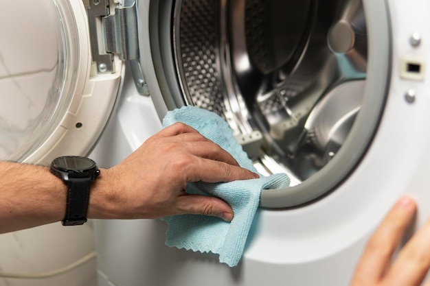 Man cleaning a dirty moldy rubber seal on a washing machine mold dirt limescale in the washing machi