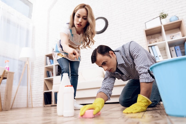 A man cleaning the floor in the apartment of a woman.