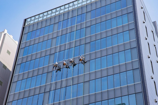 Man cleaning the glass facade of a skyscraper, high risk\
work.