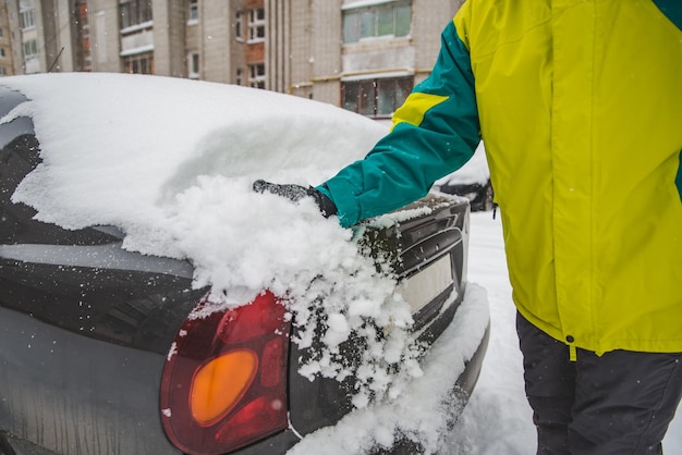 Man cleaning his car after snow storm