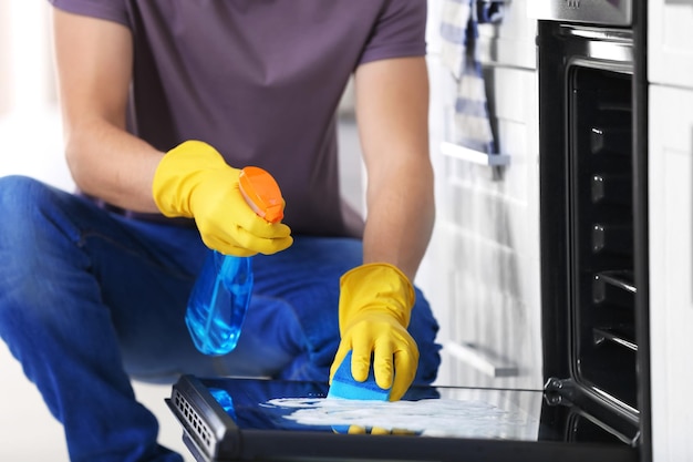 Man cleaning oven in kitchen closeup