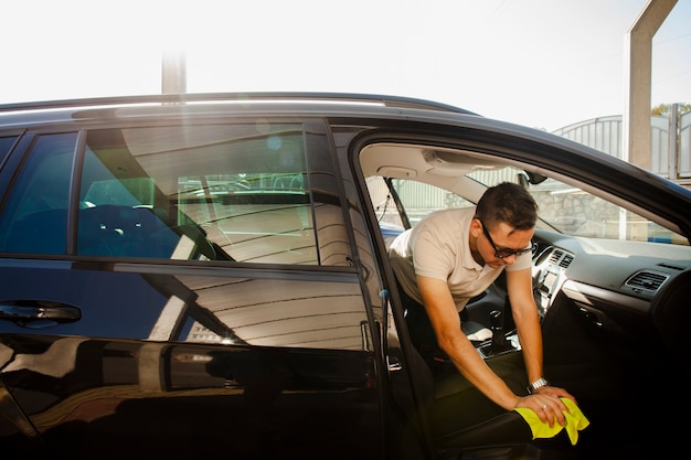 Man cleaning a seat of a black car