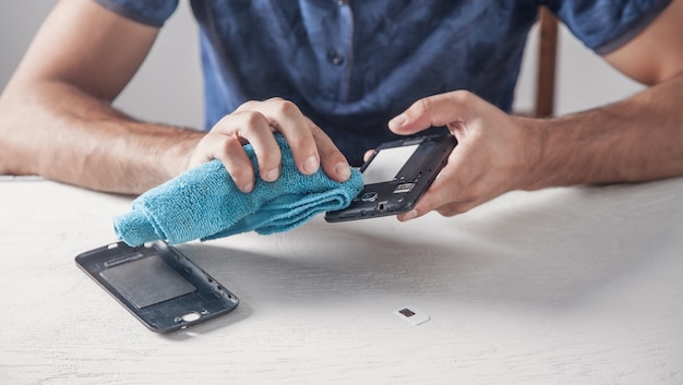 Man cleaning smartphone in office.