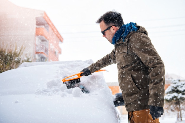 Man cleaning a snow covered car