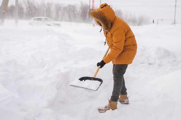 Photo man cleaning snow from sidewalk and using snow shovel winter season