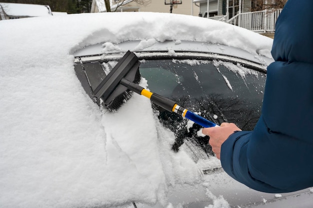 冬の降雪中に車から雪を掃除する男 白い冬の季節