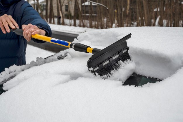 冬の降雪中に車から雪を掃除する男 冬の天気