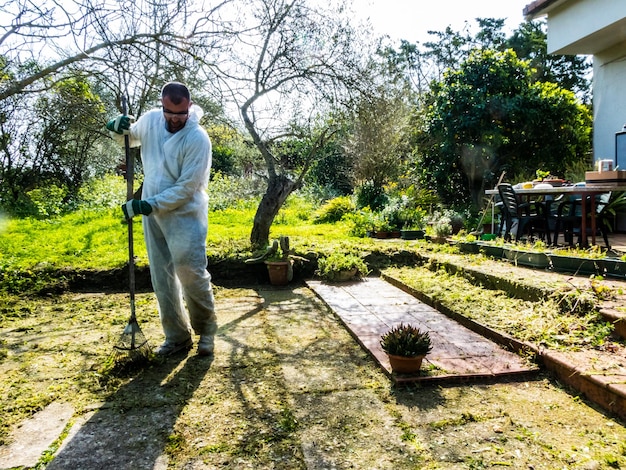 Foto uomo che pulisce con scopa di ferro in giardino