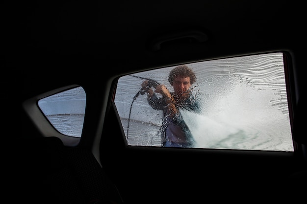 車の窓を水で掃除する人