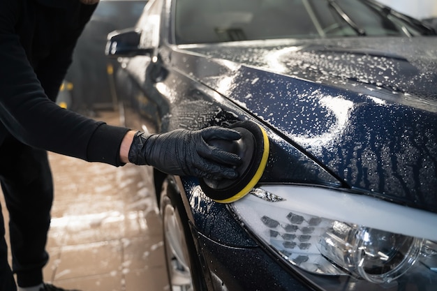 L'uomo pulisce la carrozzeria con una spugna circolare.