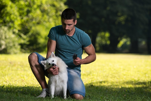 男は公園で犬のジャーマンスピッツを掃除します彼は狂っています