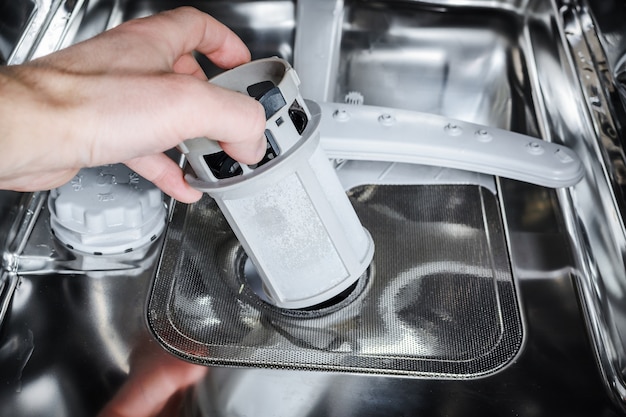 Man cleans the filter in the dishwasher.