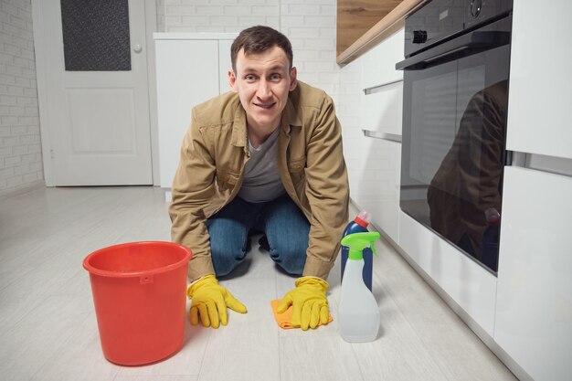 Man cleans floor with detergent and water in kitchen