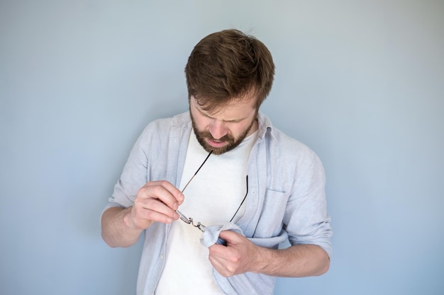 man cleans glasses from dust and dirt wiping them with his shirt