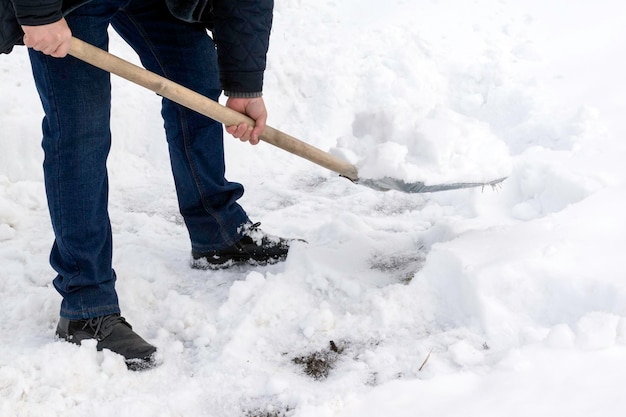 金属製のシャベルで雪を掃除する男性