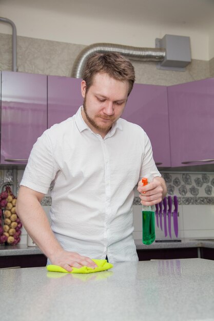 A man cleans up the kitchen Gloves and cleaner