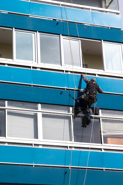 Человек чистит окна на высотном