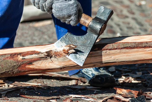 斧で幹の樹皮を掃除する男