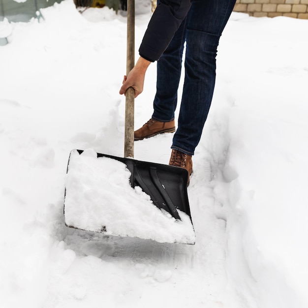 男性が自分の土地の道から雪を掃除する