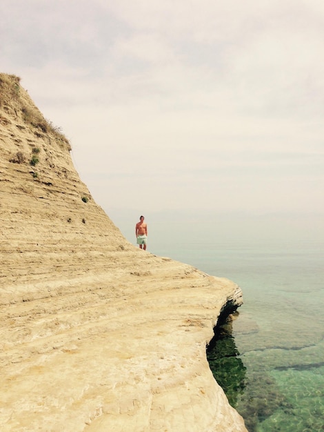 Photo man on cliff on beach against sky