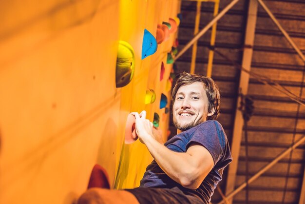 Man climber on artificial climbing wall in bouldering gym.