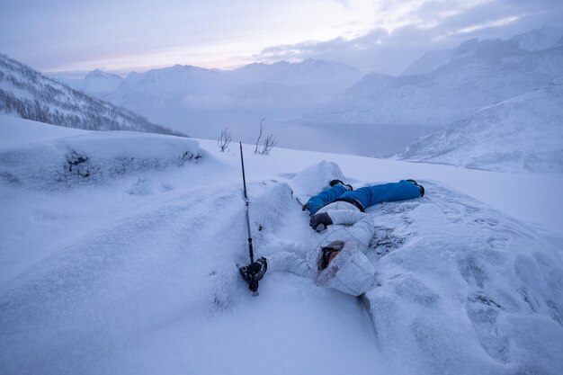 雪の丘の上に病気になった男の登山家