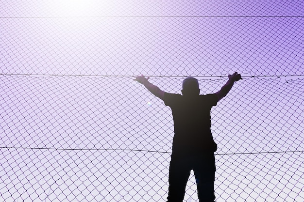 man climbing the metal fence