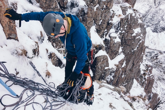 Foto uomo che si arrampica sulla montagna nella neve