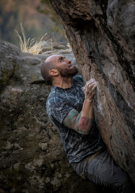 Premium Photo  A man climbing a boulder with a rock climbing outfit on his  hands.