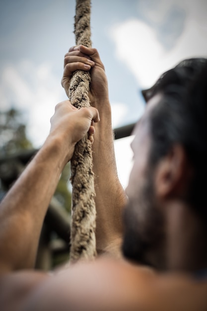 Man climbing a rope during obstacle course