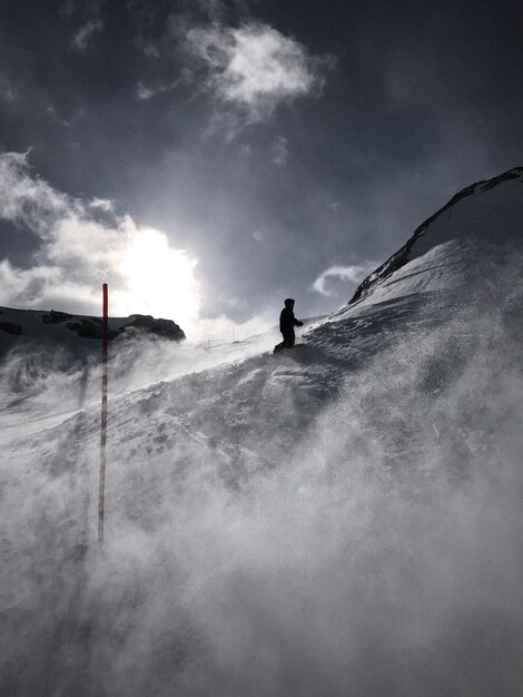 Foto uomo che si arrampica su una montagna coperta di neve contro il cielo