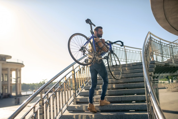 Man climbing stairs with a bike on his shoulders