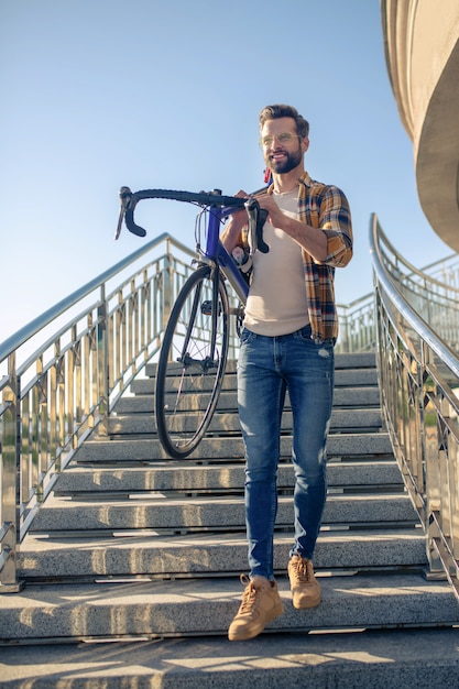 Man climbing stairs with a bike on his shoulders