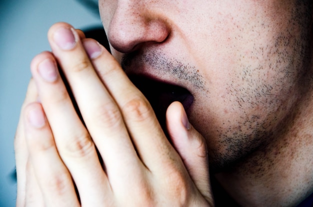 Photo a man in close-up coughs in his hand, fist. cough. virus infection. man with stubble.   covid-19