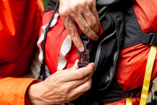 Photo man closes backpack with clasp closeup of hiking backpack being inserted hands holding plastic part