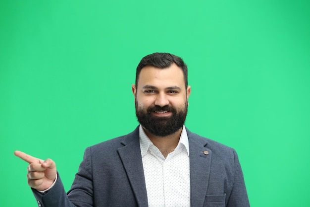 A man closeup on a green background points to the side