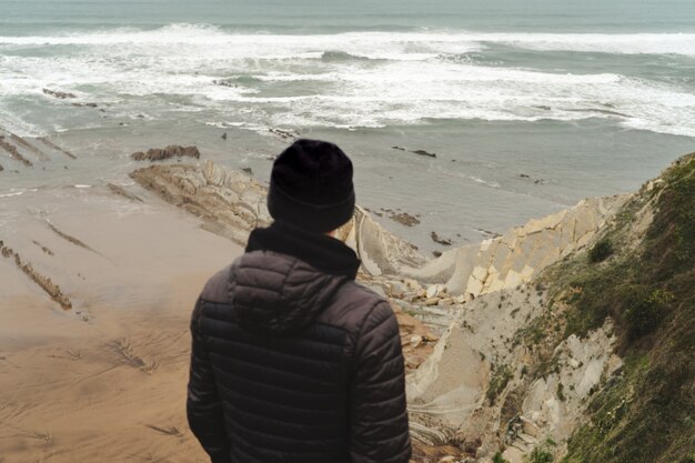 Man on the cloudy shore looking at the sea on the grass