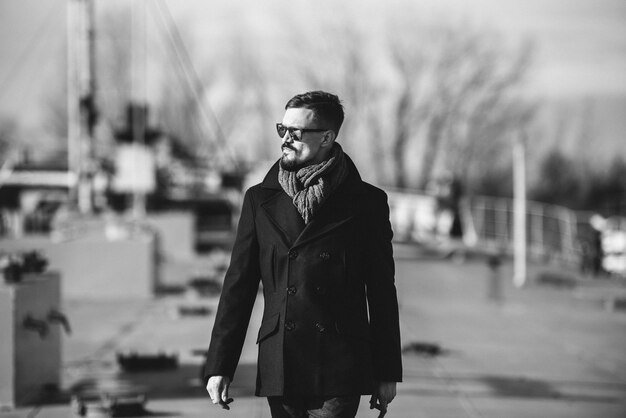 Man in a coat with a scarf poses on the street