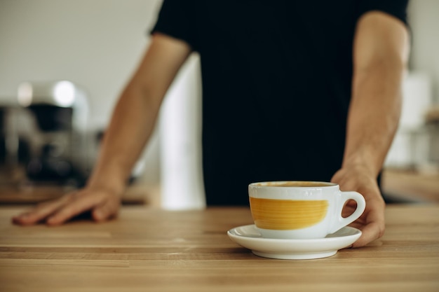 一杯のカプチーノを提供する喫茶店の男性